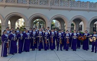 Mariachi band performing outdoors at Banana Festival event in colorful traditional attire.
